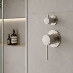 Modern bathroom faucet and shower controls on a tiled wall.